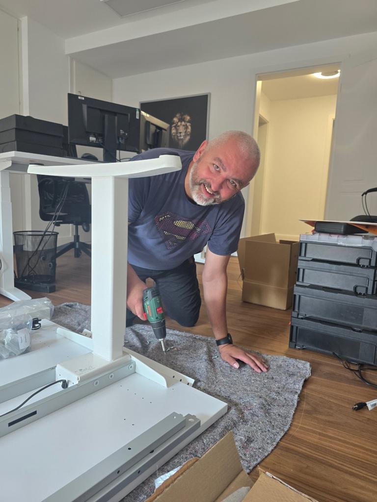 Inhaber Adrian Seidler montiert bei einem Kunden einen höhenverstellbaren Schreibtisch und übernimmt kurzfristig selbst den Serviceeinsatz nach einer Reklamation.