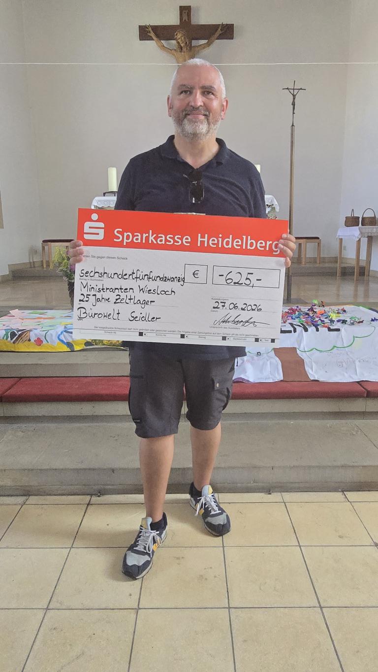 Adrian Seidler, Inhaber der Bürowelt Seidler, mit dem Spendenscheck für die Ministranten Wiesloch in der Kirche.